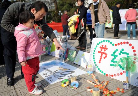 A man watches a waste exhibition with his daughter at a park in Nanchang, capital of central China's Jiangxi Province, December 5, 2009.