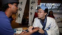 A member of China Youth Delegation who represents a Chinese doctor feels the pulse of an attendee during an activity promoting environmental protection, at Bella Center, the venue of the United Nations Climate Change Conference, in Copenhagen, Denmark, December 9, 2009.