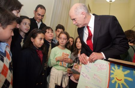 Greek Prime Minister George Papandreou (R) welcomes pupils who handed him around 56,000 signatures of citizens and 2,500 cards of children asking for a deal against climate change in the Copenhagen conference in his office in parliament in Athens, capital of Greece, December 9, 2009. 