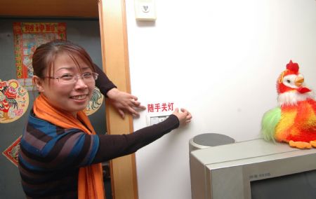 An environmental protection volunteer puts on a electricity-saving tag above a light switch at a citizen's home in Jinzhou City, northeast China's Liaoning Province, December 12, 2009. 
