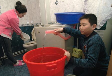 Citizens collect used washing water for toilet-cleaning at home in Jinzhou City, northeast China's Liaoning Province, December 12, 2009.