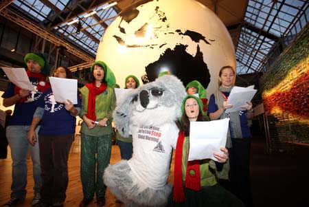 Environmental activists sing in front of an earth model, calling for people's attention on environmental protection in Copenhagen, capital of Denmark, December 12, 2009.