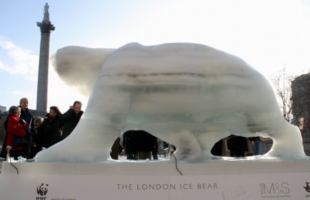 Tourists watch the melting ice sculpture of polar bear on the Trafalgar Square in London, Britain, December 12, 2009. 