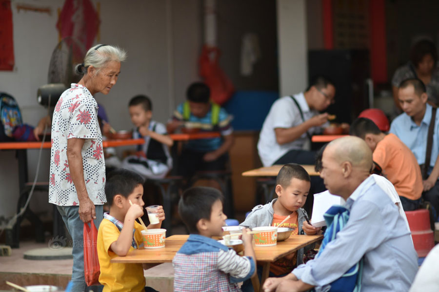 After sending her eldest granddaughter to school every morning, Huang Huiying comes to a nearby rice-noodle restaurant to collect the leftovers and take them home to feed chickens. [Photo/Sina]