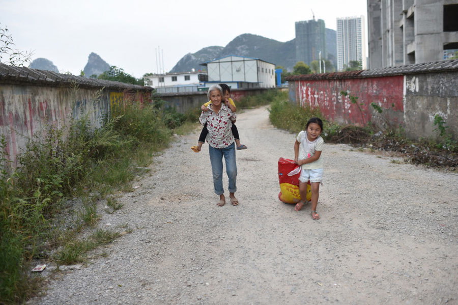 In this picture, Huang Huiying takes her two granddaughters together to local residential areas or construction sites to collect and sell scraps to earn money. [Photo/Sina]