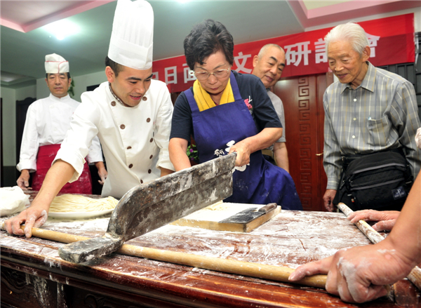 A female Japanese chef learns the local pasta-making skills of Xi'an city during a Chinese pasta cooking contest involving both Japanese and Chinese chefs in Xi'an, Shaanxi province, Sept 19, 2013. [Photo/China Daily]