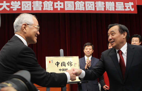 Wang Chen (right), minister of the State Council Information Office, shakes hands with Hideo Yamamoto, president of Soka University, during the launching ceremony for the Chinese section of the university's library in Tokyo on Tuesday. [Photo/China Daily]