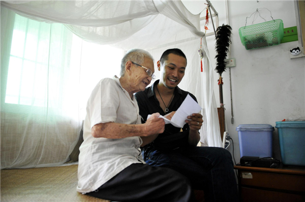 Ryotaro Harada, right, helps an elderly patient read a letter inviting him to display his paintings at a Japanese art exhibition, at a leprosy village in Foshan city, Guangdong province, July 27, 2013. 