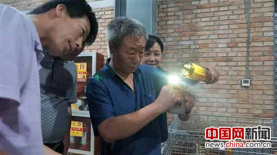 李华教授仔细察看柿子酒的色泽。