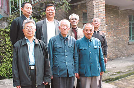 Chen Bingzhang,front row center,poses with his former colleages in front of their former office building at the nuclear base in Baitao,which is in Chongqing.