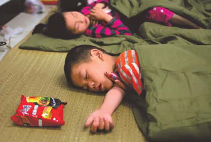 A boy falls asleep in Fuzhou stadium last week. The stadium was used to house people displaced by floods in Jiangxi province.