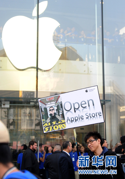 A man carries a placard which bears the words 'Open Apple Store' and features a picture of South Korean rapper Psy at the gate of Apple's largest store in Asia, located in the city's commercial street of Wangfujing. 