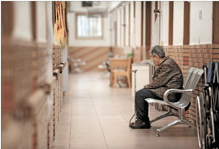 A senile dementia or Alzheimer's disease patient sits lonely in the corridor of a nursing home in Shanghai. 
