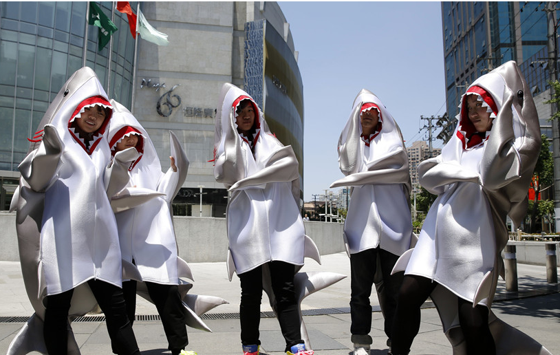 Young persons, dressed as sharks, call for people to stop eating shark fins on a street in Shanghai on May 23, 2014. The non-governmental organization WildAid China launched the 'I'm FINished with FINS' campaign in Shanghai on Friday in efforts to raise awareness of shark finning and help residents pledge not to eat shark fins. [Photo: China News Service / Tang Yanjun]
