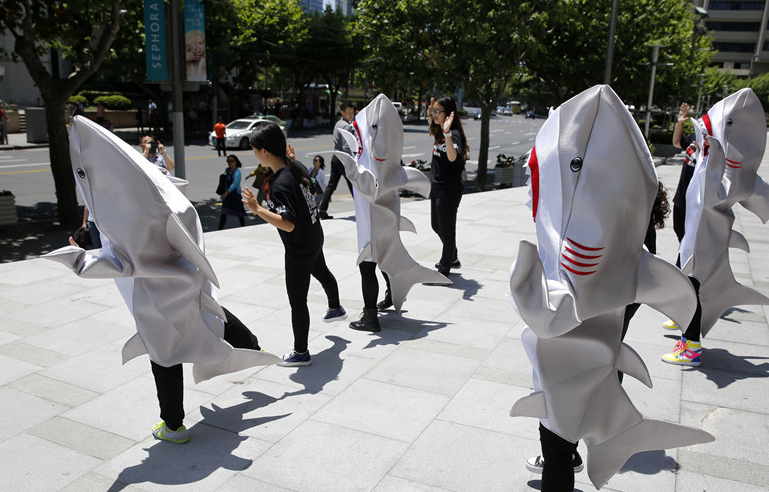Young persons, dressed as sharks, call for people to stop eating shark fins on a street in Shanghai on May 23, 2014. The non-governmental organization WildAid China launched the 'I'm FINished with FINS' campaign in Shanghai on Friday in efforts to raise awareness of shark finning and help residents pledge not to eat shark fins. [Photo: China News Service / Tang Yanjun]