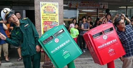 People pose with two letter boxes which were bent to one side by Super Typhoon Soudelor in Taipei, Taiwan, Aug 9, 2015.
