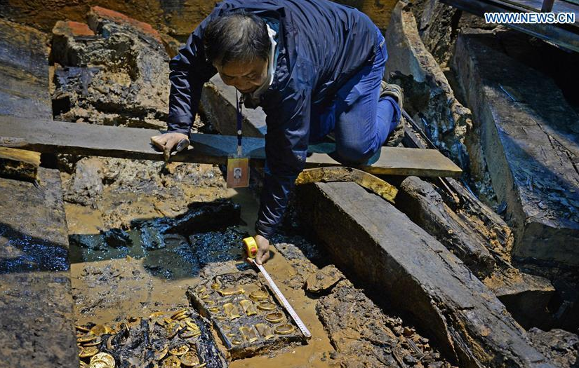 An archaeologist measures the gold items in an aristocrat's tomb that dates back to the Western Han Dynasty (206 BC - 24 AD), in Nanchang, capital of east China's Jiangxi Province, Nov. 17, 2015.
