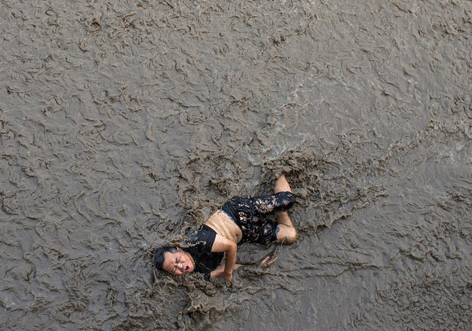 A man who fell off an embankment of Qiantang River was luckily saved by a journalist before being swept off by the river’s rising tide in Hangzhou, East China's Zhejiang province, on Monday.[Photo/qq.com] 