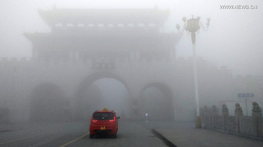 A car runs in the fog-bound county seat of Runan, central China's Henan Province, Jan. 3, 2017. A red alert for fog in large parts of China was issued by the National Meteorological Center on Tuesday. (Xinhua/Sun Kai) 