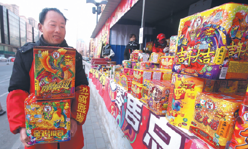 A worker carries fireworks to put on display at a temporary sales outlet in Beijing's Chaoyang district on Monday.[Chen Xiaogen/for China Daily]