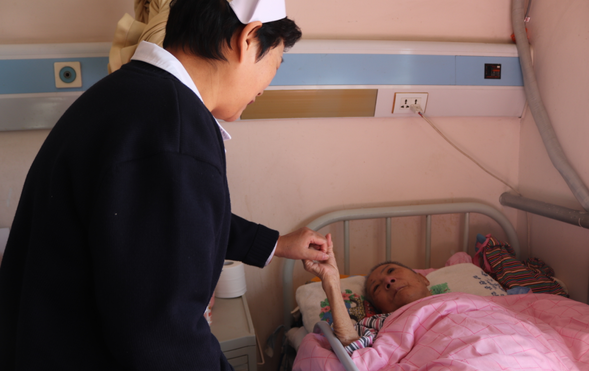 A nurse holds a patient’s hand in Beijing Songtang Care Hospital. [Photo by Zhang Liying/China.org.cn]