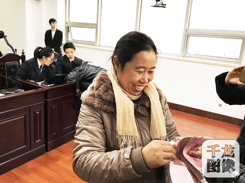 北京东城法院南区的第二法庭内，13位外来务工者领到欠薪28万元。图为外来务工者申改霞开心地数刚刚领到的工资。千龙网记者 查甜甜摄