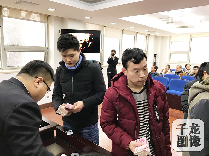 北京东城法院南区的第二法庭内，13位外来务工者领到欠薪28万元。图为外来务工人员现场领拖欠的工资。千龙网记者 查甜甜摄