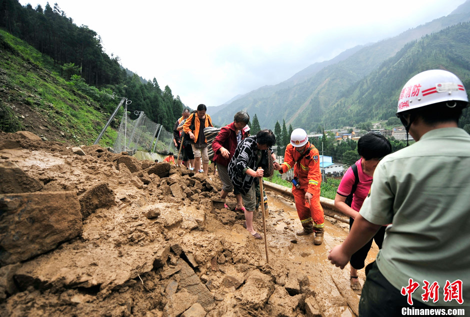 四川彭州遭遇暴雨泥石流 民众乘坐挖掘机转移 