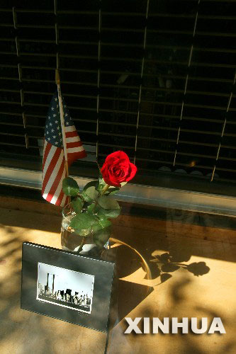 9月10日，在美国纽约世贸中心附近的一家商店外，一朵玫瑰、一面国旗和一幅世贸中心遭袭前的照片摆放在街边。纽约各界9月10日举行各种纪念活动，纪念“9·11”恐怖袭击事件五周年。 新华社发 