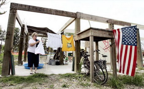 图文：美国妇女在重建的房屋构架旁晾衣服