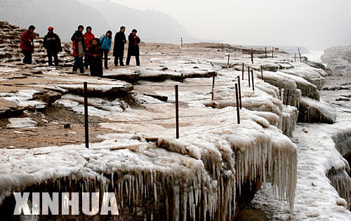 12月24日，游人在壶口景区观看冰凌景观。眼下，地跨晋陕两省的壶口景区冰凌景观已颇具规模，吸引了众多游人和摄影爱好者。