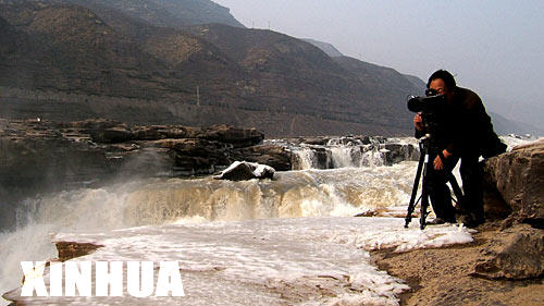 12月24日，一名摄影爱好者在壶口景区拍摄冰凌景观。眼下，地跨晋陕两省的壶口景区冰凌景观已颇具规模，吸引了众多游人和摄影爱好者。