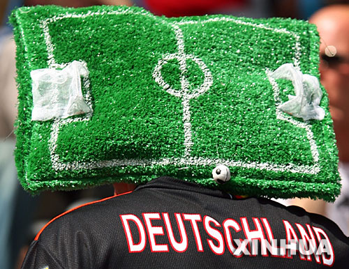 这是6月9日，一名球迷在德国慕尼黑戴着以“球场草坪”为造型的帽子迎接德国世界杯的到来。 新华社发