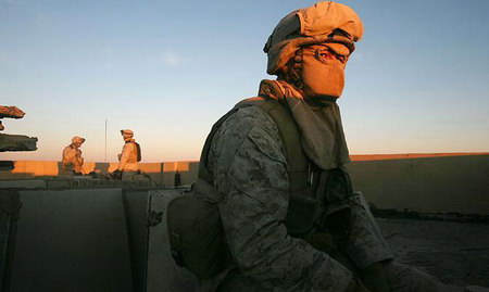 一名美国海军陆战队士兵在伊拉克乡村住宅屋顶上视察。