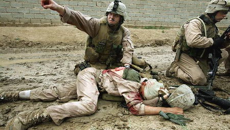 一名美军士兵用纱布压住战友的伤口。
