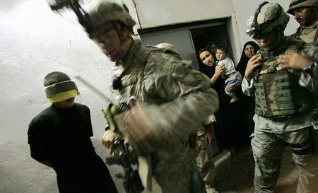 美军和伊拉克士兵对一名涉嫌参与宗教暴力的男子进行搜查。