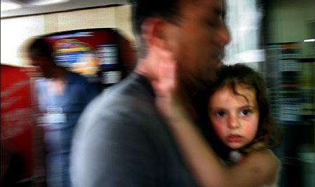 在黎巴嫩真主党对以色列北部城市袭击之后，一名以色列男子抱着女儿跑向医院。