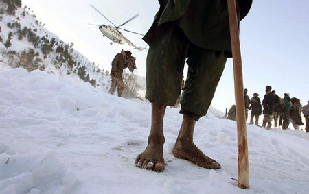 在巴基斯坦一个不通公路的山区,一名赤脚的村民在等待直升机的救援物品。