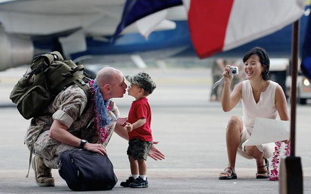 2006年5月，美国海军陆战队士兵返回夏威夷基地后同儿子亲吻，妻子在一旁用相机记录这一温馨时刻。
