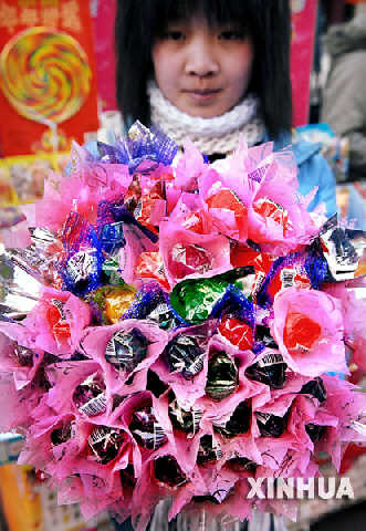 2月13日，一位女孩在展示用糖果制成的花束。     情人节前夕，银川市部分商家推出一系列用糖果制成的“甜蜜礼物”，受到许多年轻消费者的喜爱。     新华社记者 李紫恒 摄 