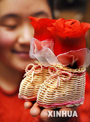 银川某商场里，一位女孩在展示一款玫瑰花造型的情人节礼物(2月8日摄)。 近日，银川的商场里出现一种由一对小鞋组成的情人节礼品，取意“合鞋”，寓意情侣间情感和谐、融洽。