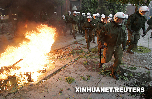 6月2日，在德國(guó)北部城市羅斯托克，防暴警察走過(guò)一處燃燒的路障。羅斯托克當(dāng)天爆發(fā)大規(guī)模反全球化示威活動(dòng)。警方與示威人群發(fā)生沖突，造成100多名警察受傷，數(shù)十名示威者被捕。