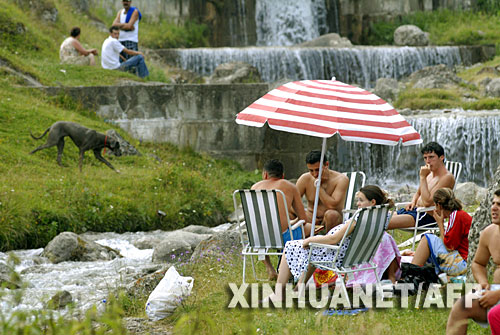 7月22日，在罗马尼亚中部布什泰尼市，人们在水边避暑。持续数日的热浪在罗马尼亚继续肆虐，气温已超过42摄氏度。截至21日，高温天气至少造成11人死亡。 新华社/法新 