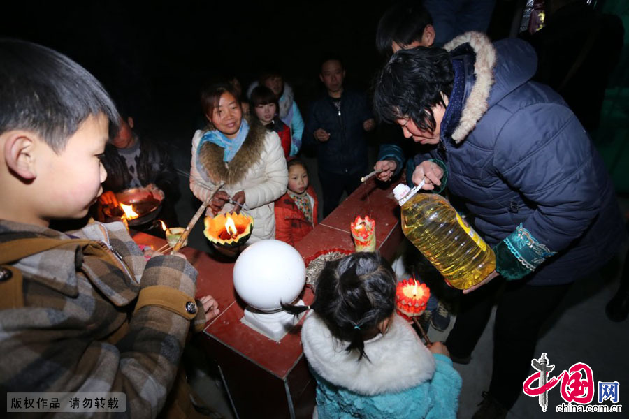3月9日，河南原阳县陈杏兰村，一位村民为孩子们的灯盏添上食用油。