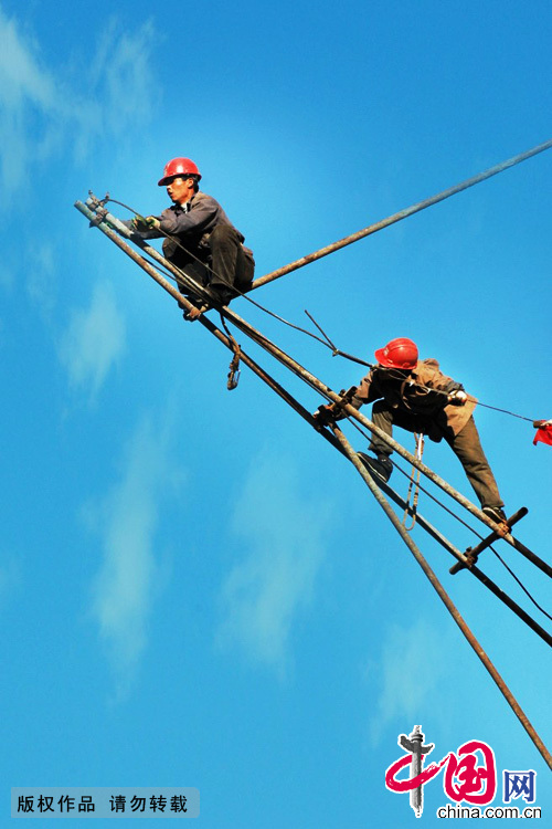  2007年11月23日，北京西城区，建筑工地上的架子工人爬上最高点完成他的工作。每挪一步，都是拿生命在移动。中国网图片库 郑永摄