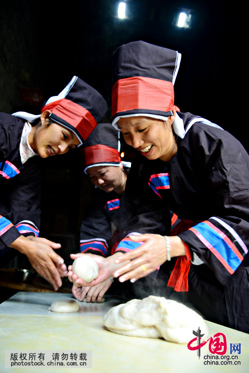 她们把舂好的糯米团用手捏揉成约一公分厚、饭碗大小的大圆饼，拍打、揉捻，让糍粑更富Q感弹性。中国网图片库 黄旭胡摄 