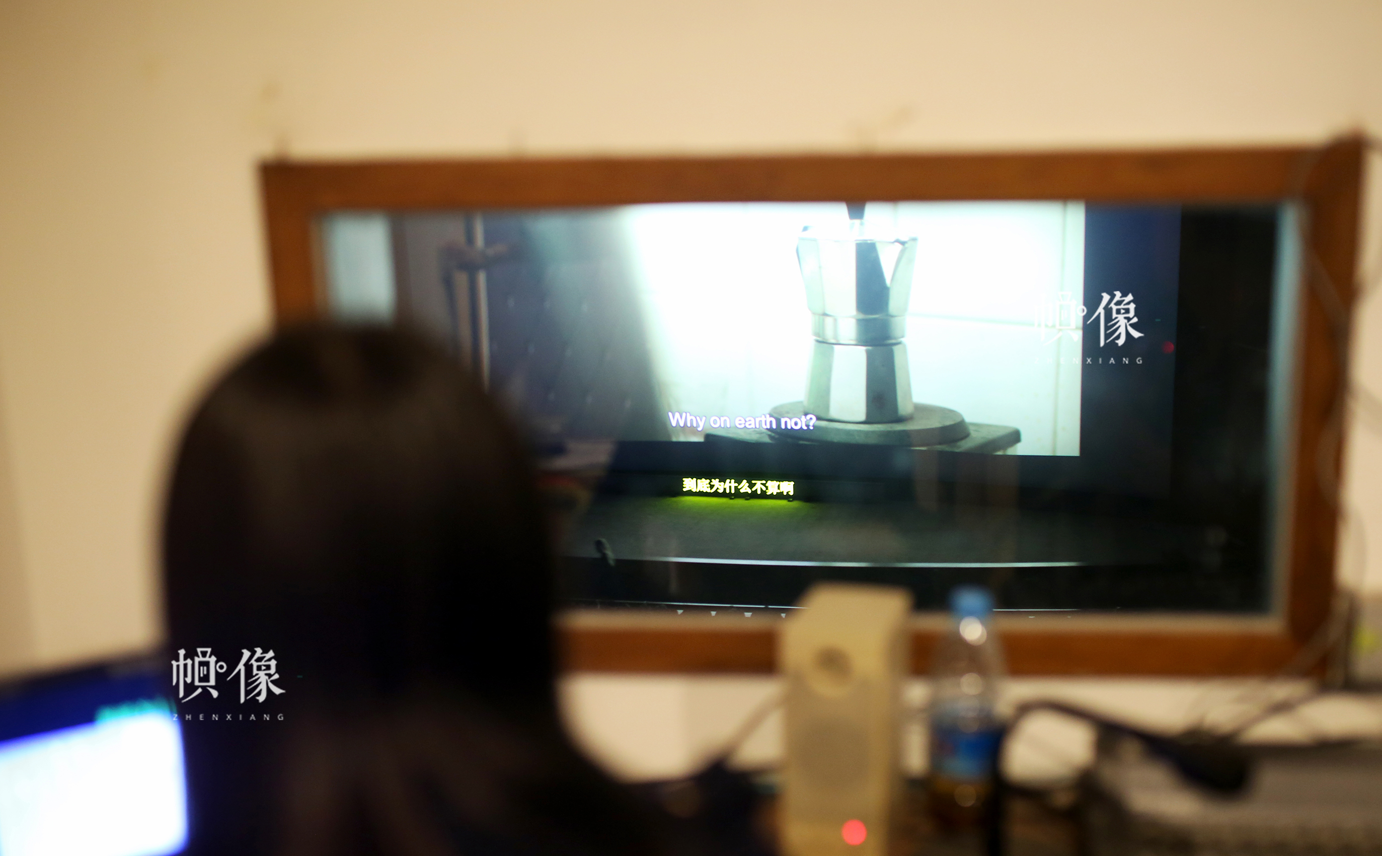 周立烨透过身侧的玻璃看着电影银幕，为电影加中文字幕。中国网记者 焦源源 摄