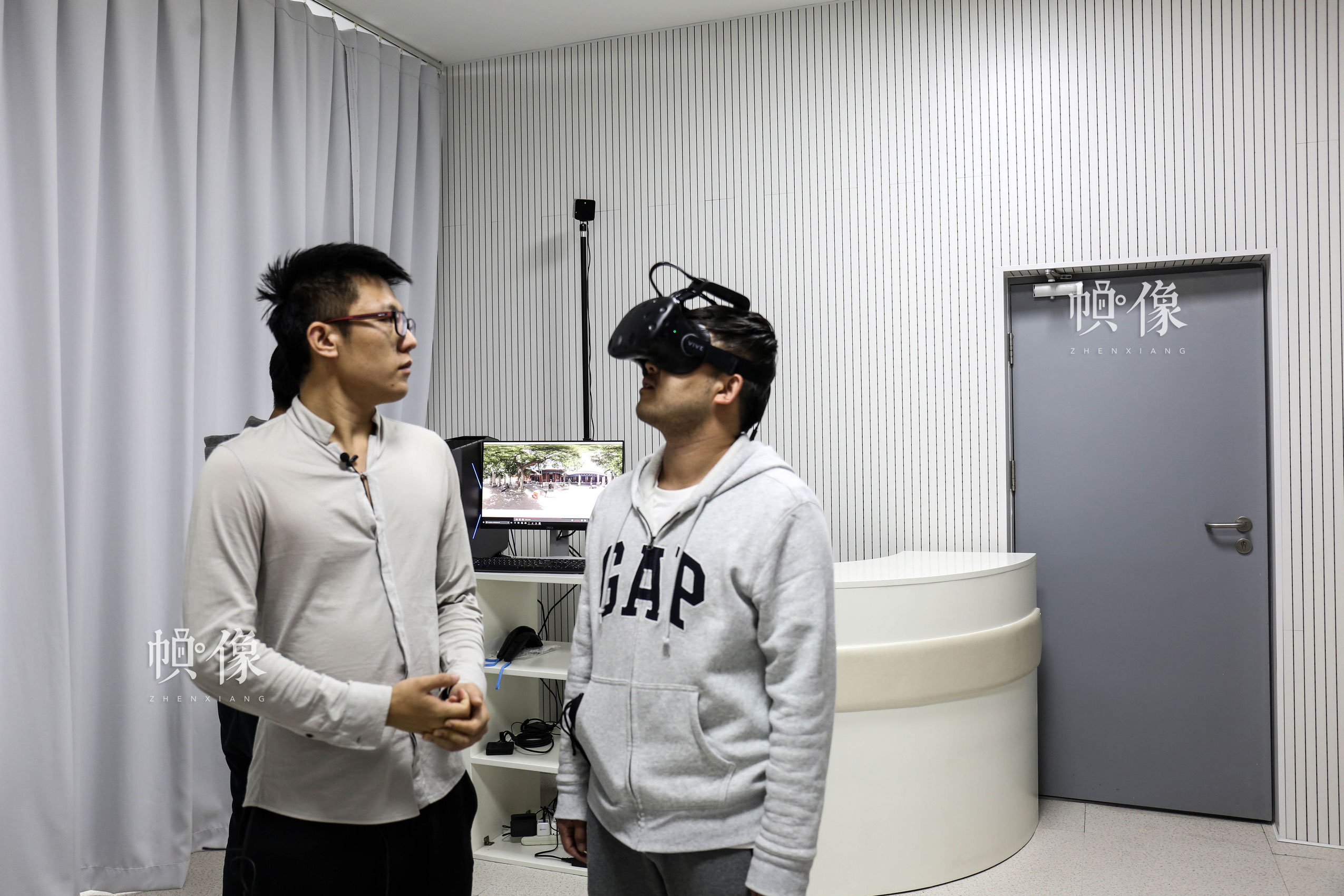 朝阳规划艺术馆VR(Virtual-Reality-)技术体验室，图为讲解员（左）在介绍引导体验者（右）体验东岳庙场景VR技术。中国网记者 赵超 摄