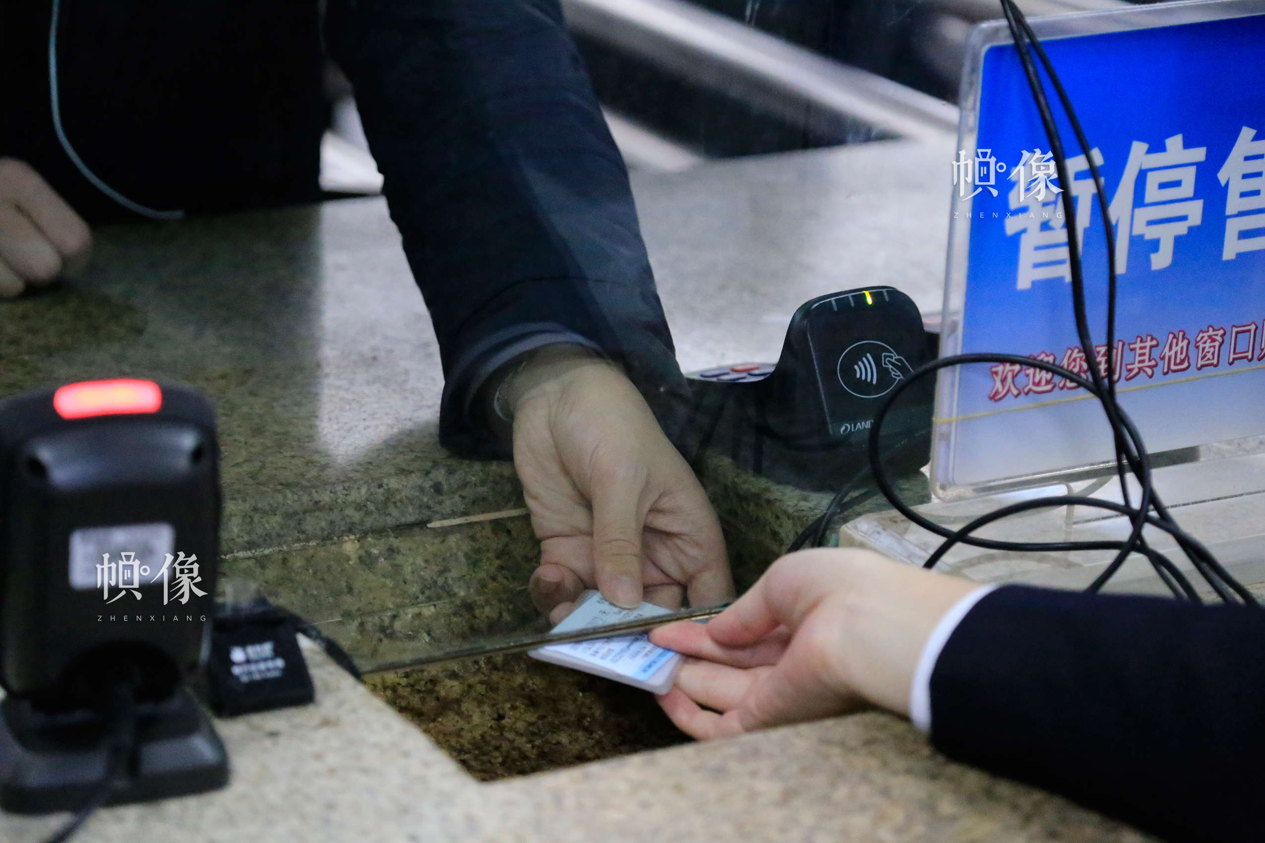 北京南站某一售票窗口内，一位售票员与乘客通过窗口底部的凹槽传递乘客购买的火车票及证件。中国网实习记者 韩依 摄