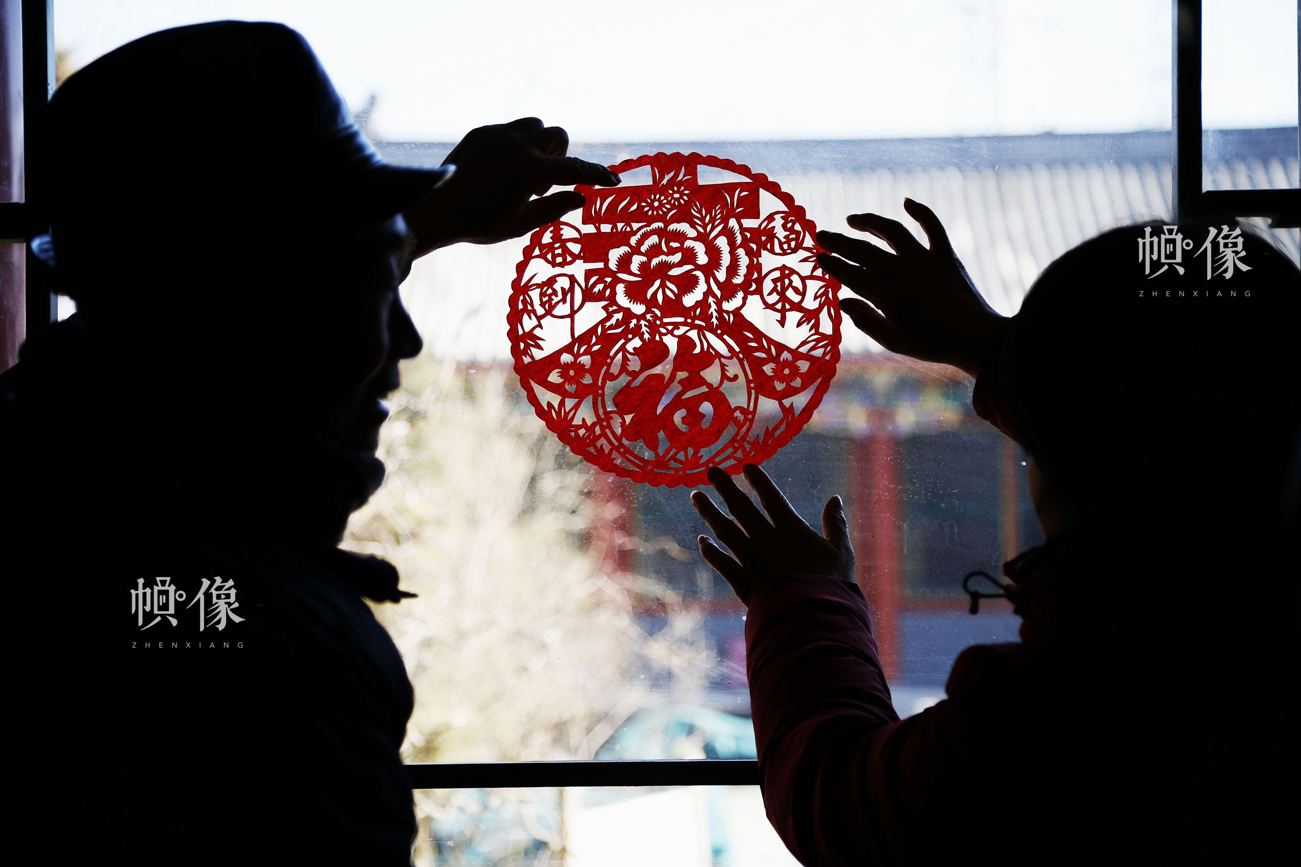 姚雨林和他的学生一起将剪好的窗花贴在窗户上。中国网实习记者 张钰 摄